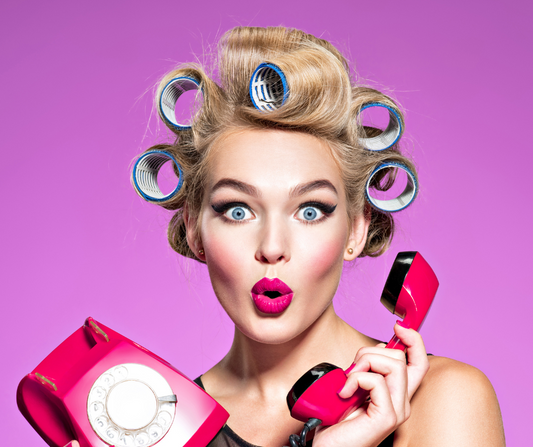 blonde woman wearing hair curlers and holding a pink phone