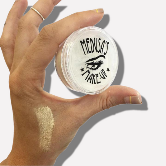 Hand holding a jar of Medusa's Make-Up product with a swatch on the skin.