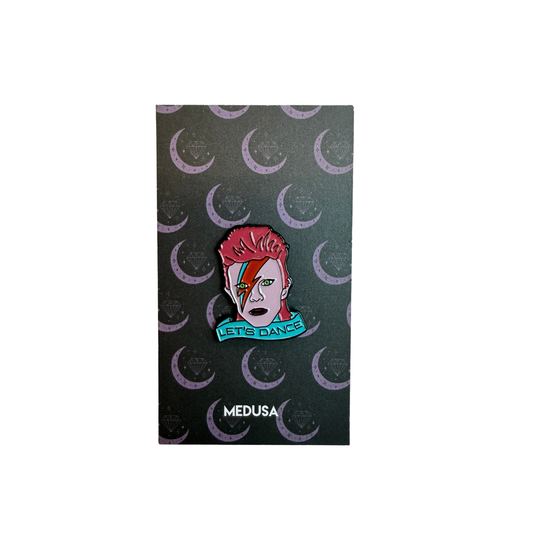 Pin with a design of a person with red hair and a rainbow, with 'Let's Dance' text, on a black background with crescent moon patterns. Brand 'MEDUSA' visible.