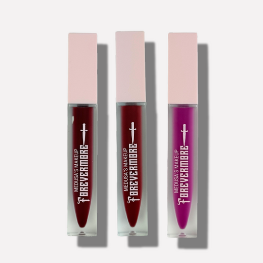Three lip glosses in different colors with their packaging on a white background