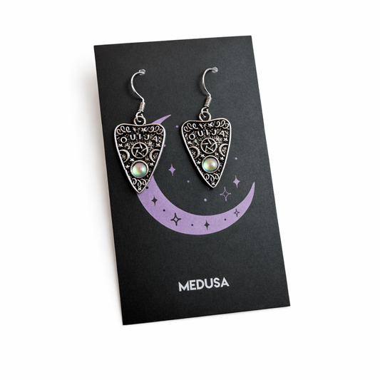Pair of silver Medusa-themed earrings on a black card with 'Medusa' branding.