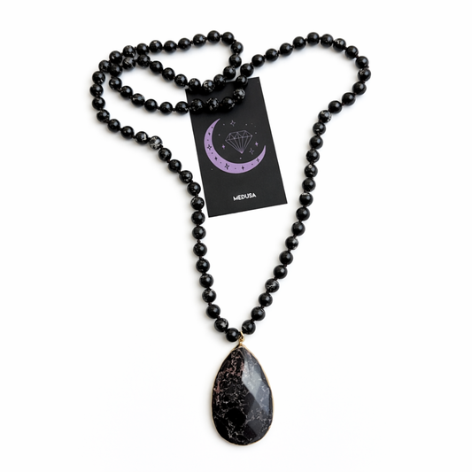 Black beaded necklace with a teardrop pendant on a white background