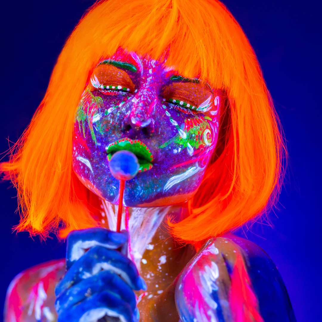 Model wearing neon orange wig wig neon pigment allover her face