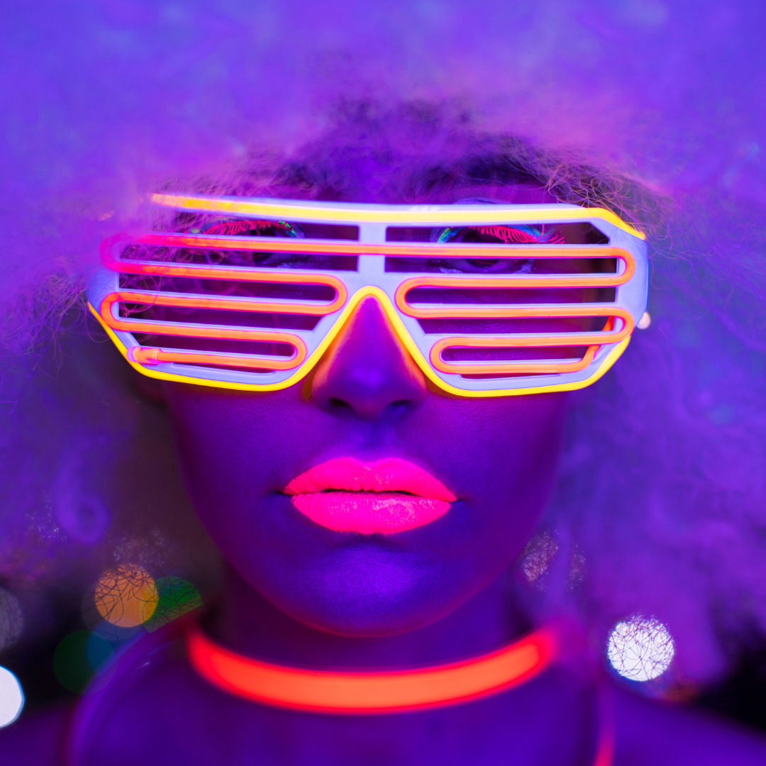 Model wearing neon sunglasses, neon lipstick, neon jewelry