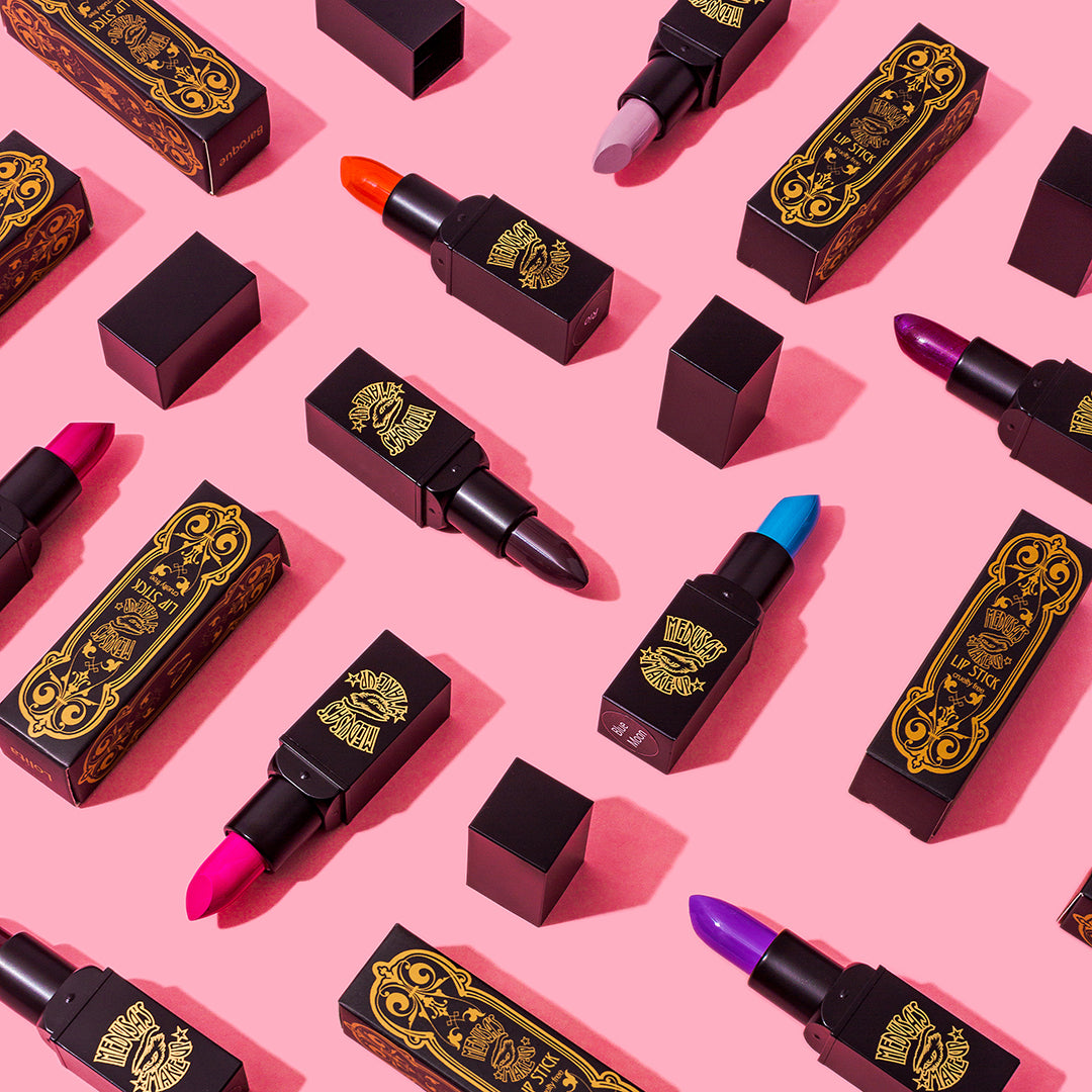 various Medusa's Makeup lipsticks displayed on a pink background