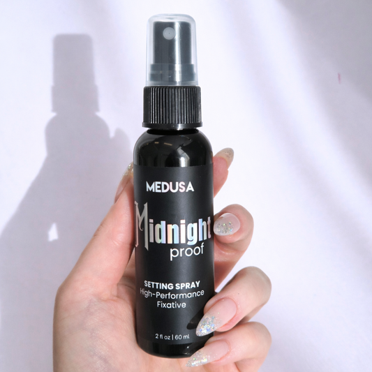 Hand holding a black spray bottle labeled 'Medusa Midnight Proof' against a white background