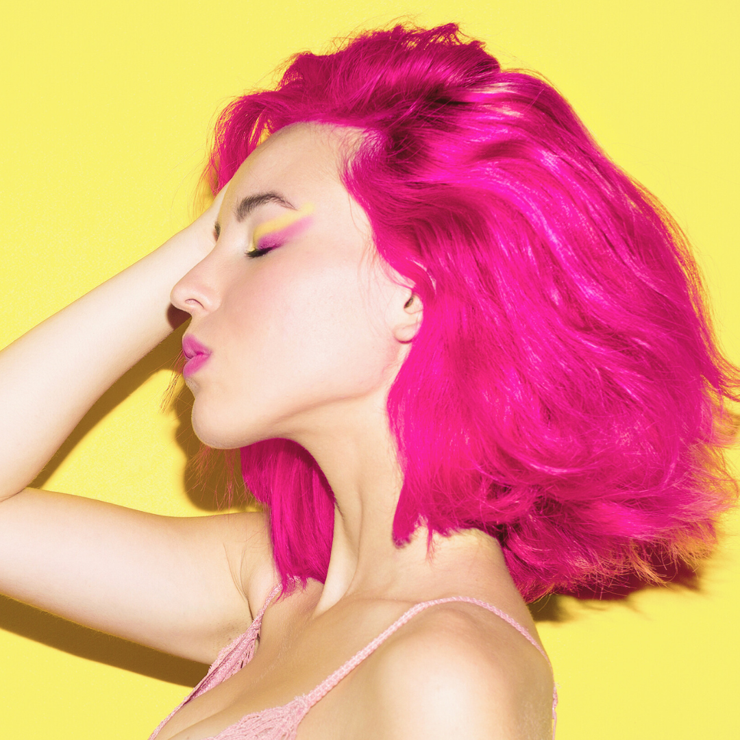 Model with Lunar Tides Neon Dragonfruit hair on a yellow background