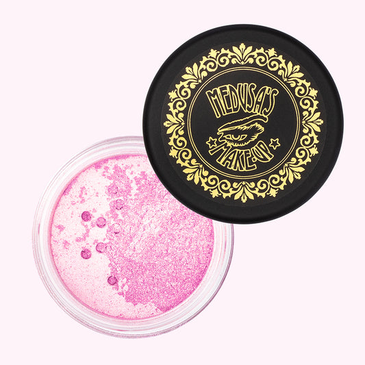 A jar of mineral blush powder with iridescent peachy color, displayed alongside its decorative black lid featuring gold designs.