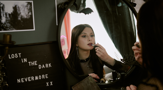 gothic girl putting on makeup in the mirror