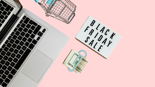 Laptop and mini shopping cart, cash, and sign that says black friday sale