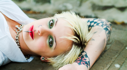 woman with blonde hair, piercings, and tattoos laying down on a deck 