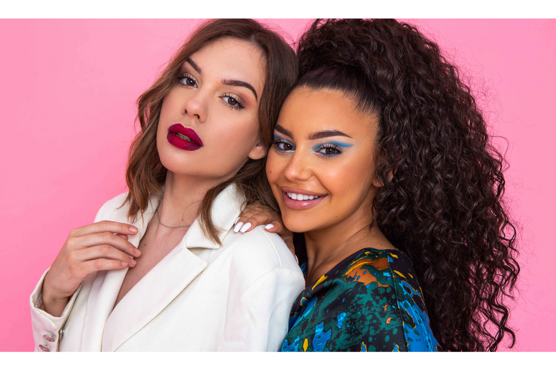 women with bold makeup posing against a pink background