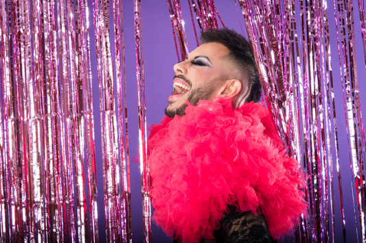 male presenting person wearing colorful makeup and a pink feather boa