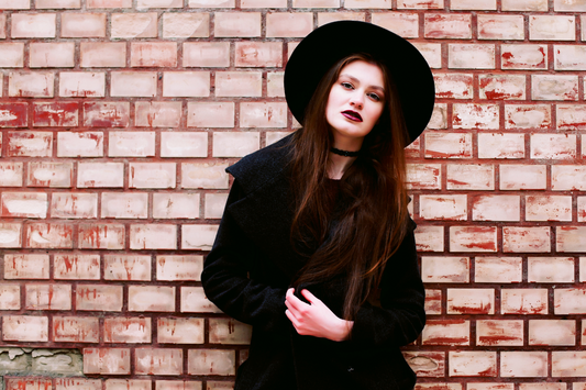 gothic woman leaning against a brick wall