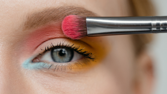 woman applying coral eyeshadow with a flat brush