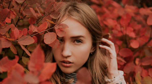 woman posing behind some fall leaves