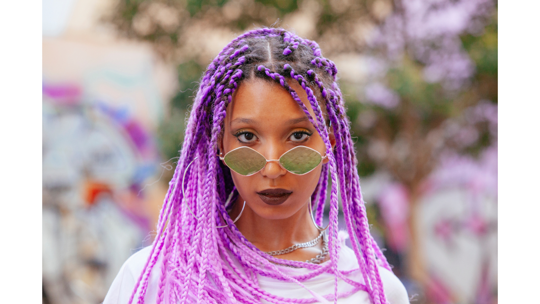 black woman with purple braids and round sunglasses
