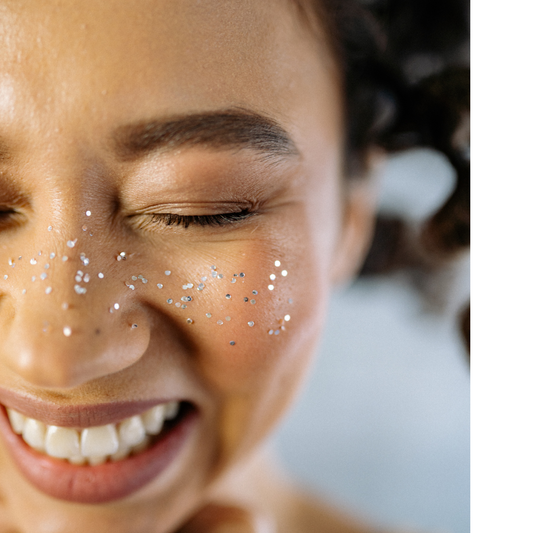model closing her eyes and smiling with glitter across her nose and cheeks