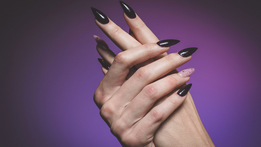 hands with long black nails on a purple background