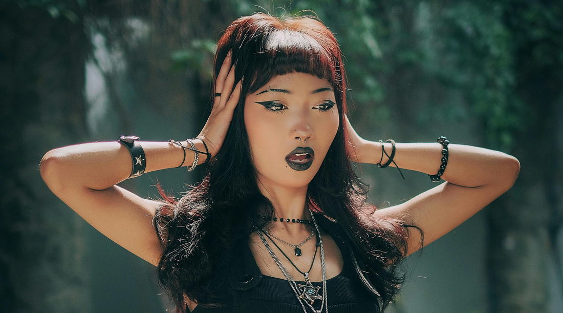woman with winged eyeliner and black lipstick posing with gothic accessories