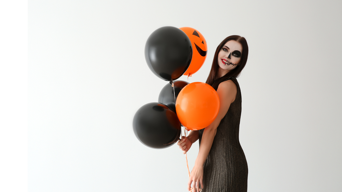 woman with skeleton makeup holding black and orange balloons