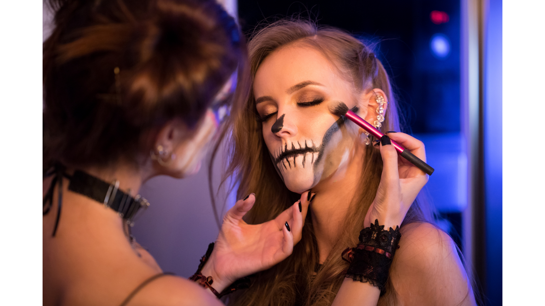 woman getting skeleton makeup painted on by another person