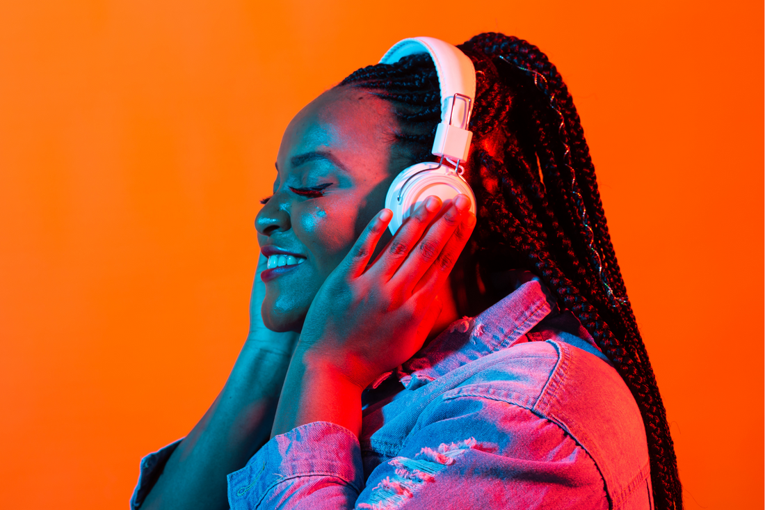 dark skinned woman with braids smiling and listening to music with headphones