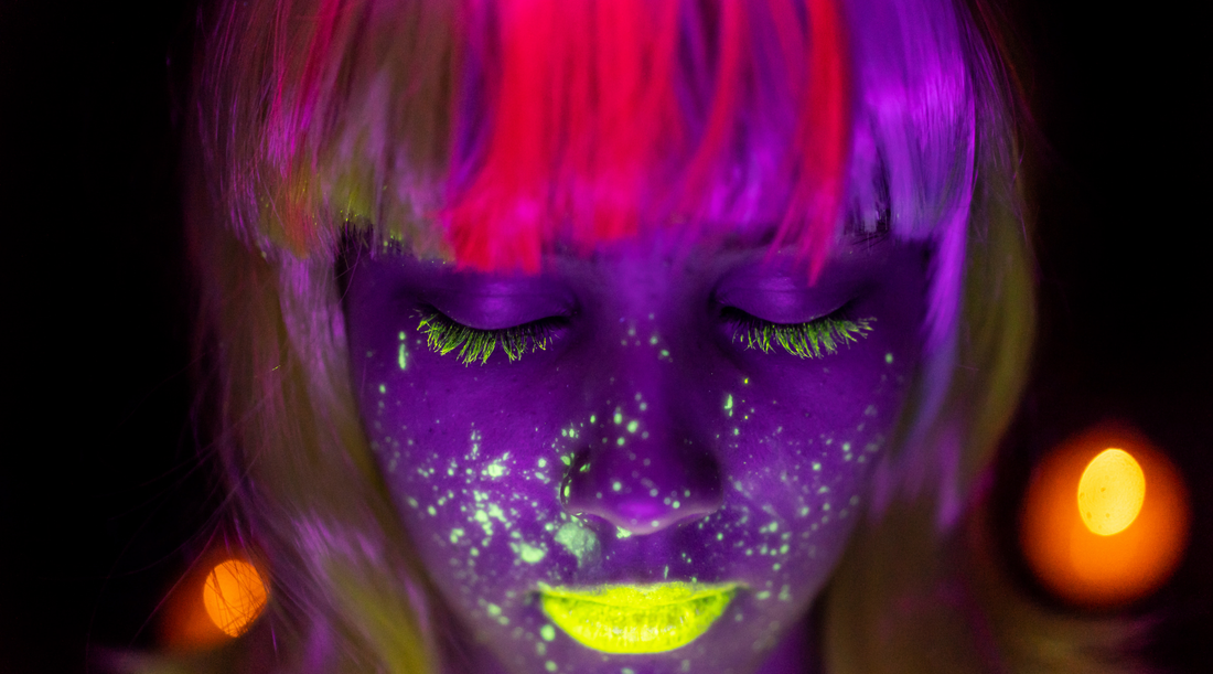woman with neon hair and neon yellow makeup under blacklight