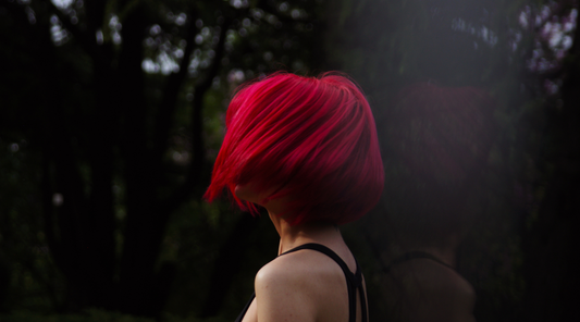 woman with short, vibrant red hair swishing her hair in the wind