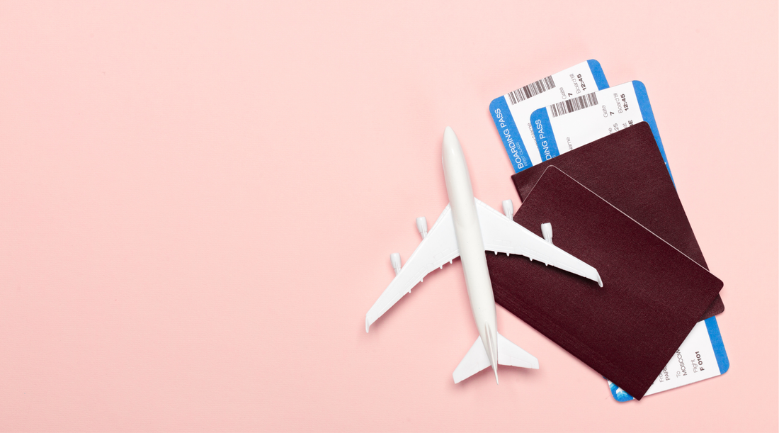 passports, plane tickets, and a mini plane prop on a pink background