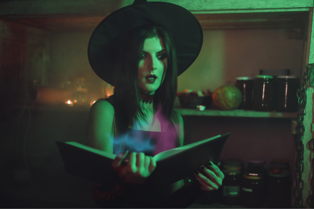 witch with black hat holding an open book of spells