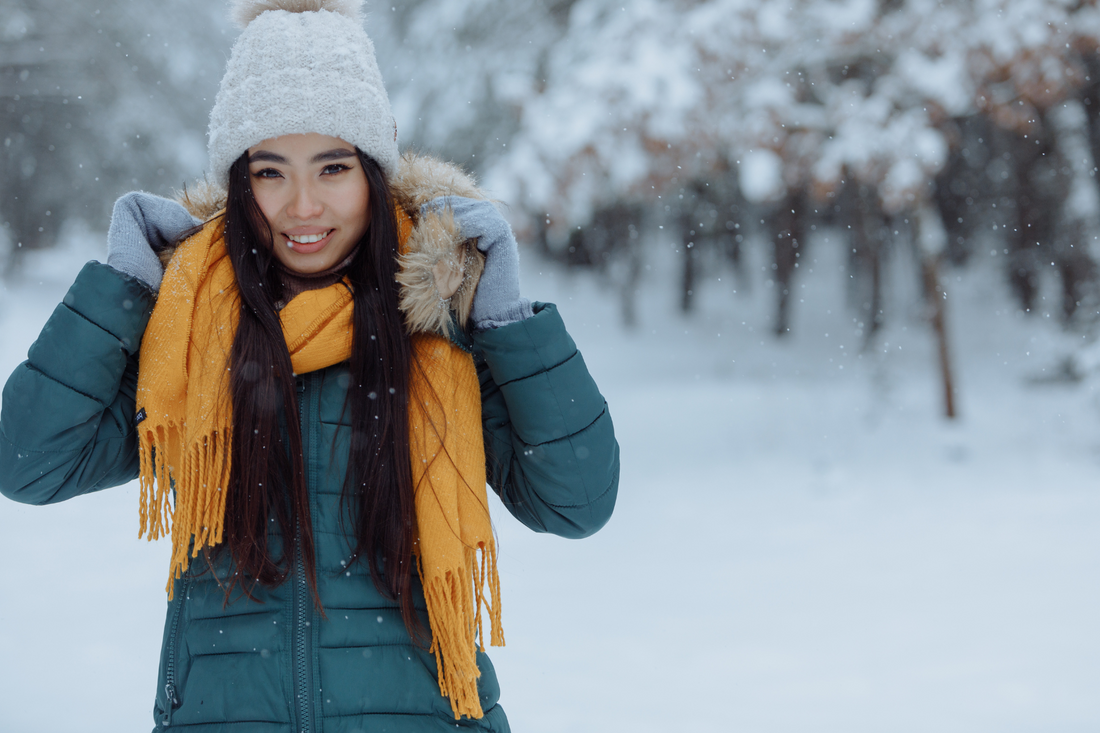 woman with long dark hair and winter hat and scarf in the snow