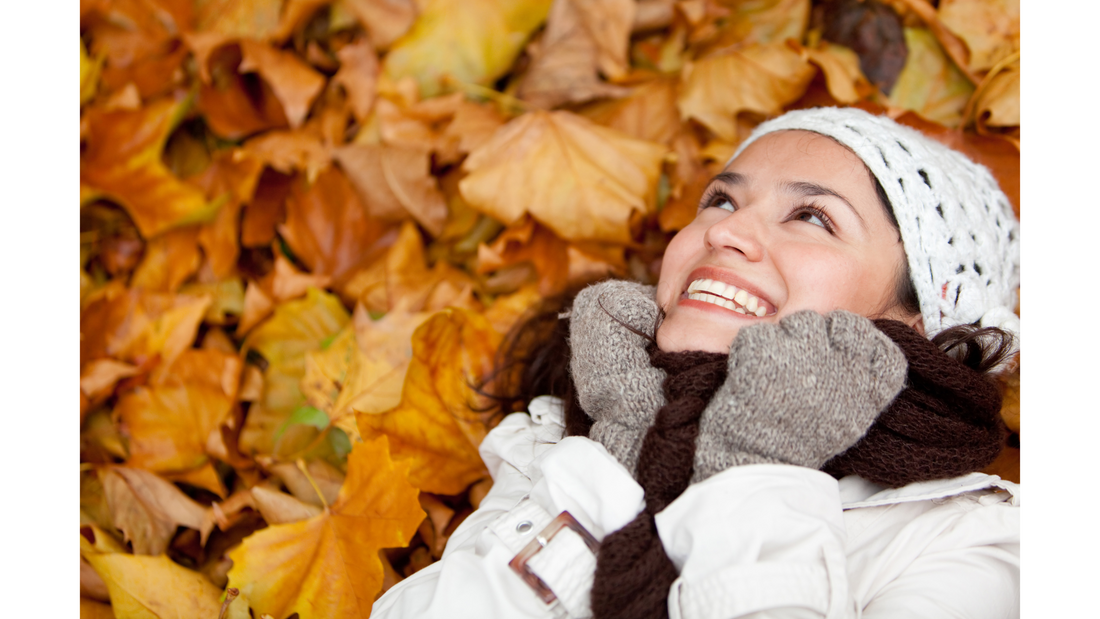 woman laying in fall leaves smiling