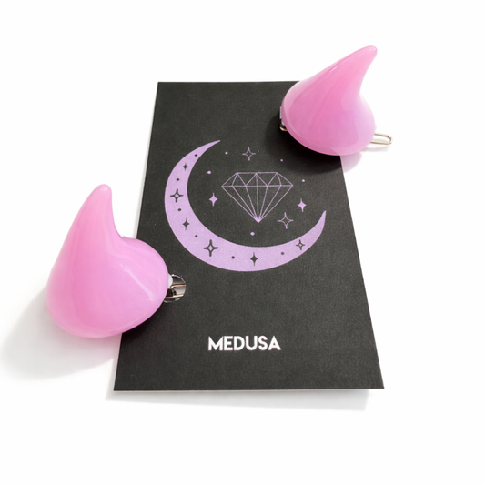 Pink hair clips with a 'Medusa' design on a black card