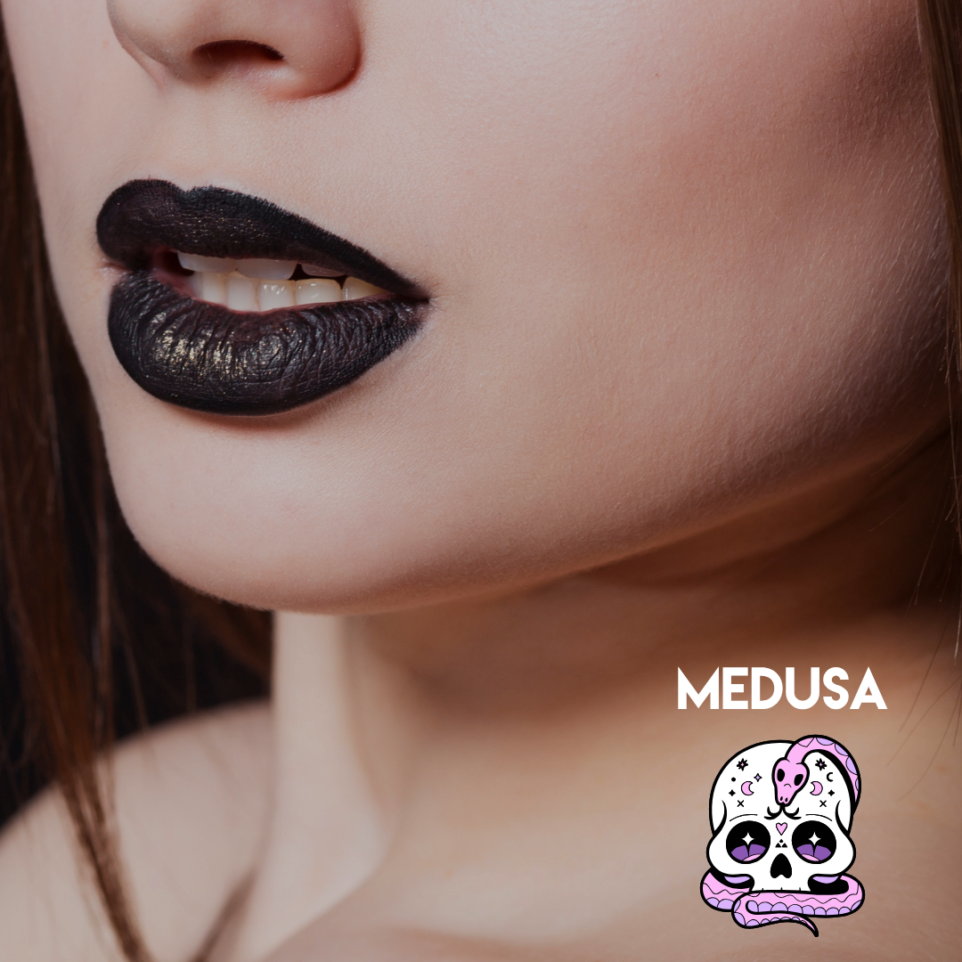 Close-up of a model's lower face wearing glossy black lipstick with a textured, metallic finish. The brand name 'MEDUSA' is printed in white text alongside a small cartoon skull and snake logo in the bottom right corner.