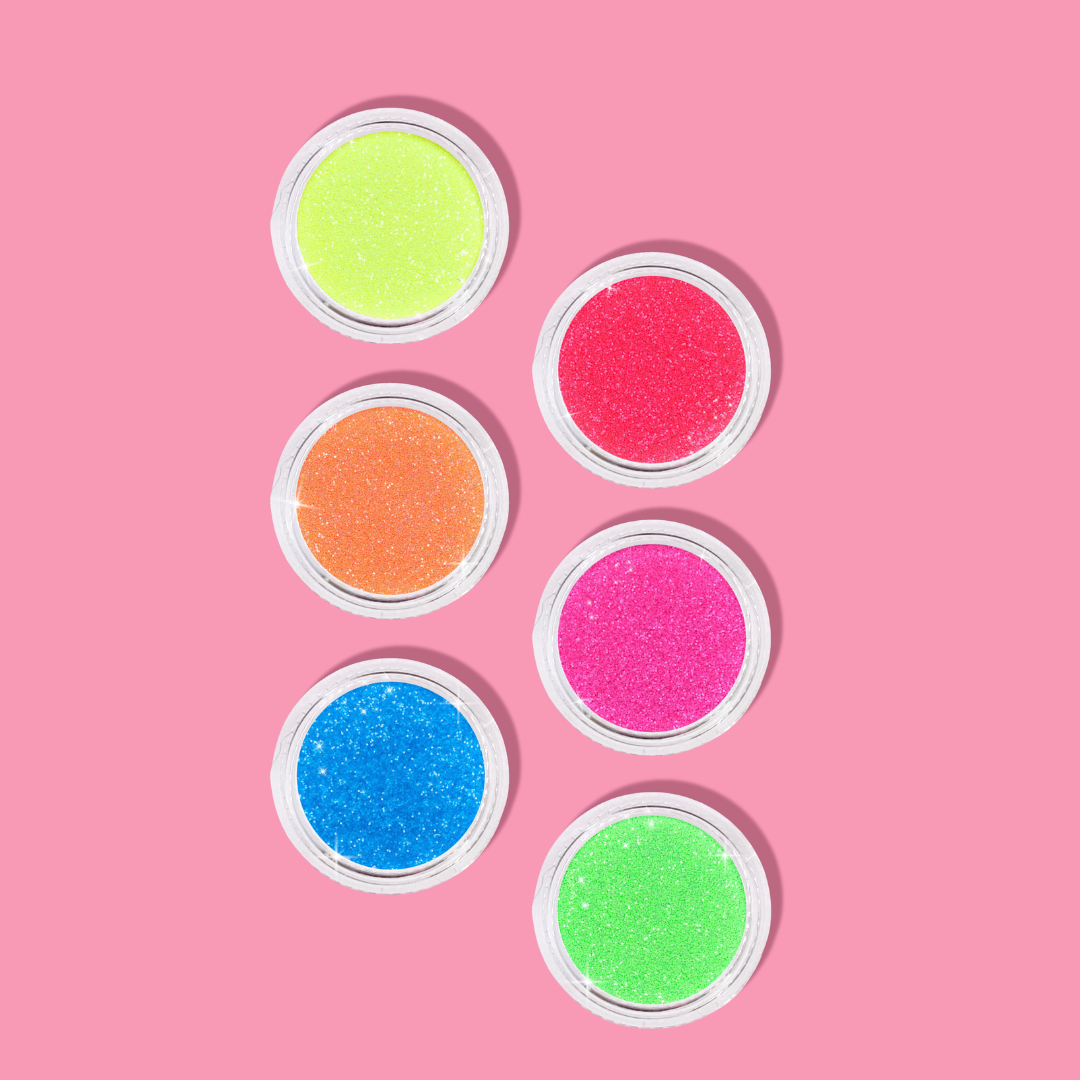 Six small containers of colorful glitter on a pink background