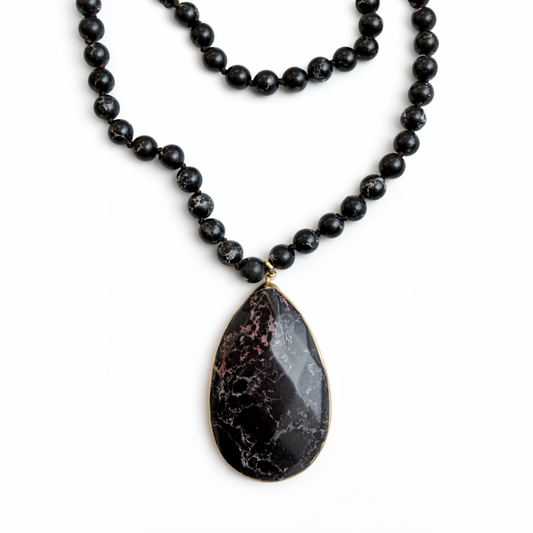 Black beaded necklace with a teardrop-shaped pendant on a white background