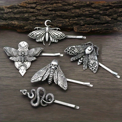 Silver moth-shaped hair pins on a wooden surface
