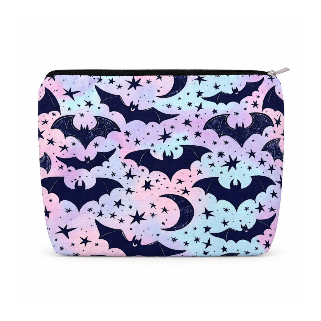 A zippered pouch featuring a whimsical pattern of black bats, crescent moons, and stars over pastel pink, purple, and light blue clouds on a dark navy background, shown against a plain white background.