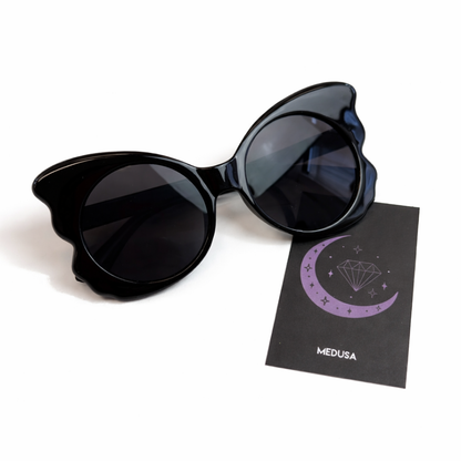 Black cat-eye sunglasses with a branded card on a white background