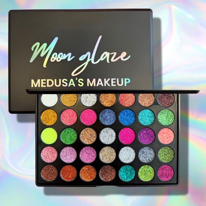 Makeup palette with colorful shades and 'Moon Glaze Medusa's Makeup' branding on a rainbow gradient background.