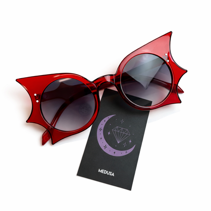 Red sunglasses with bat-wing design on a white background