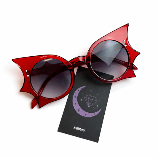 Red sunglasses with bat-wing design on a white background