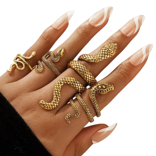 Hand wearing multiple gold snake-shaped rings on a white background