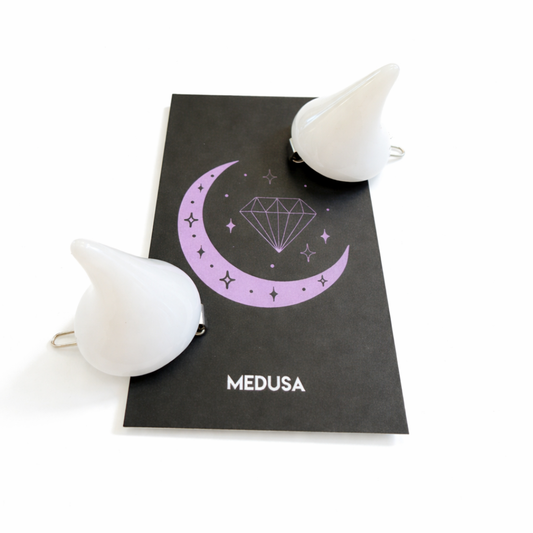 White hair clips with a crescent moon and diamond design on a black card with 'MEDUSA' branding.