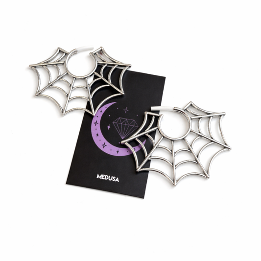Spider web-shaped earrings with a black card featuring a purple design and 'MEDUSA' branding on a white background.