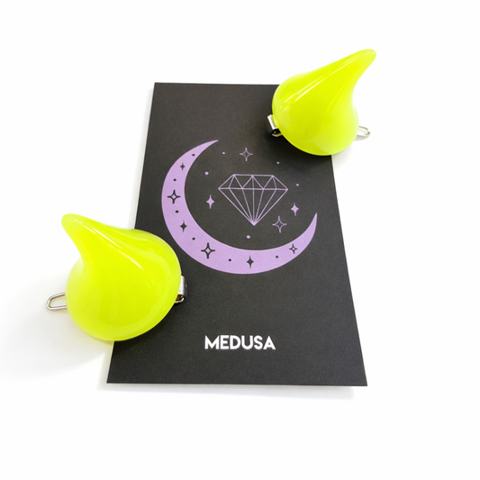 Yellow hair clips on a black card with 'Medusa' branding