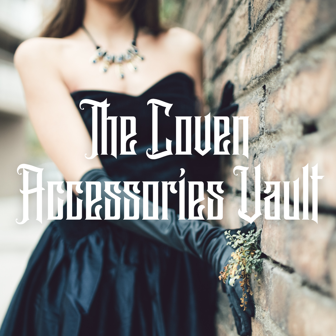 A woman in a black strapless dress and long black gloves leans against a brick wall, wearing a silver-toned statement necklace and a floral bracelet. Large white gothic text reads 'The Coven Accessories Vault' across the center.