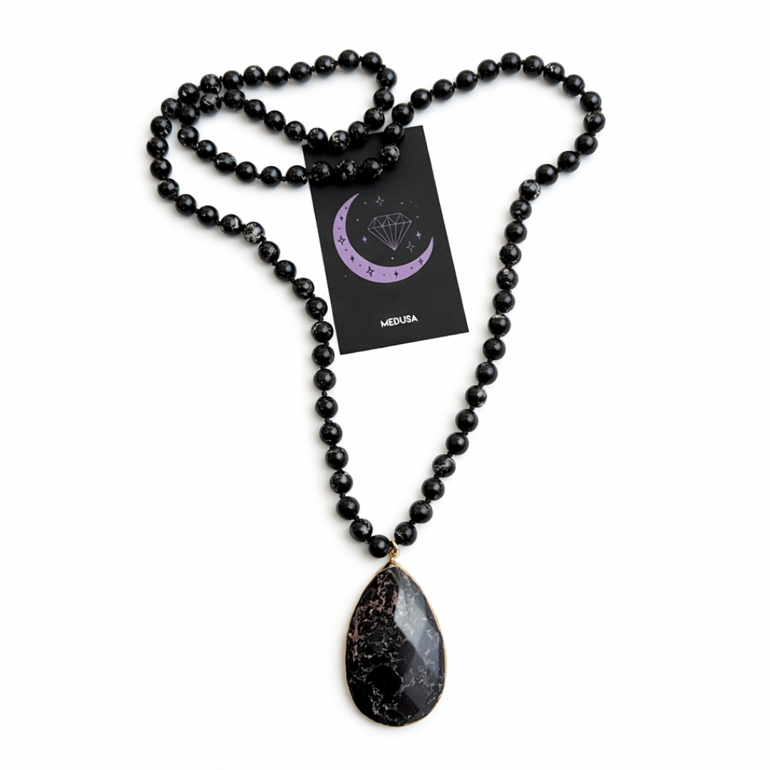 Black beaded necklace with a teardrop pendant on a white background