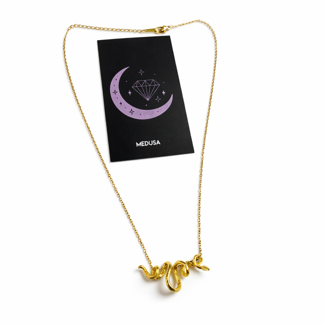 Gold snake necklace on a white background with a black card displaying 'Medusa'.